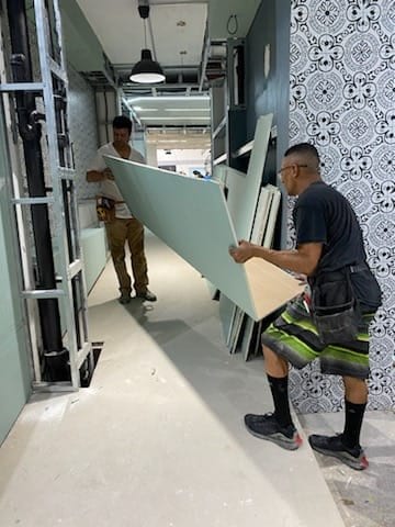 Two SQR crew members carrying a composite panel through a retail interior