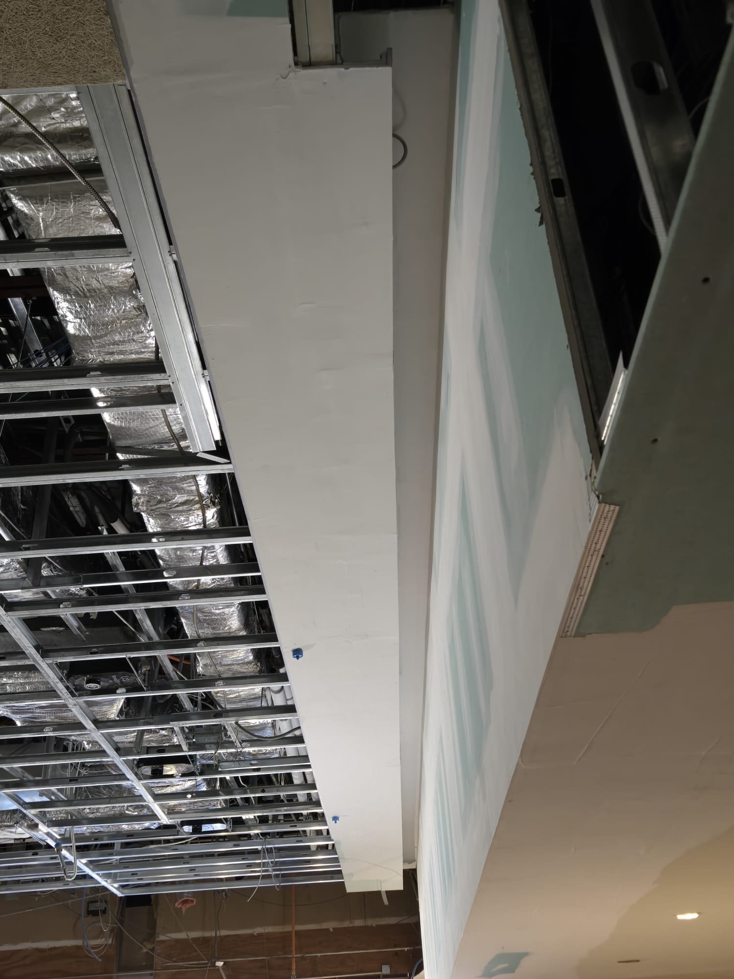 Tall curved ceiling transition beside exposed ceiling framing