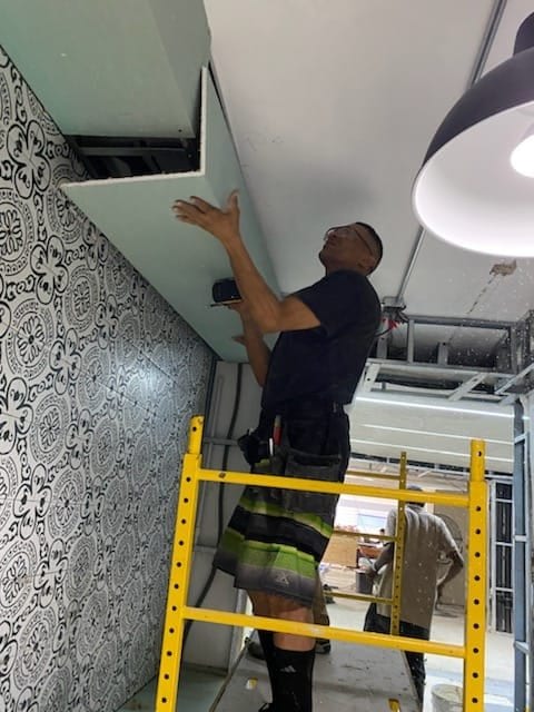 Installer fitting decorative wall panels from a yellow scaffold
