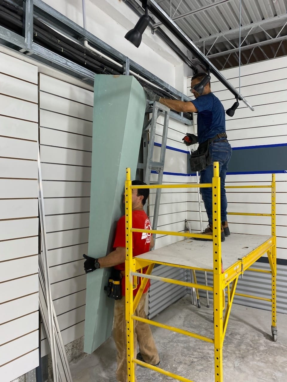 SQR installer fitting a tall wall panel from a yellow scaffold