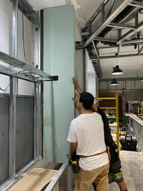 Installer working beside exposed wall and ceiling framing