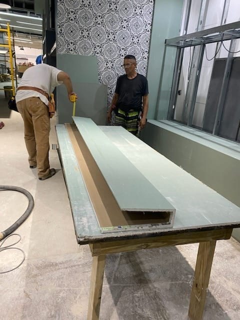 SQR crew fabricating a long composite panel on a worktable